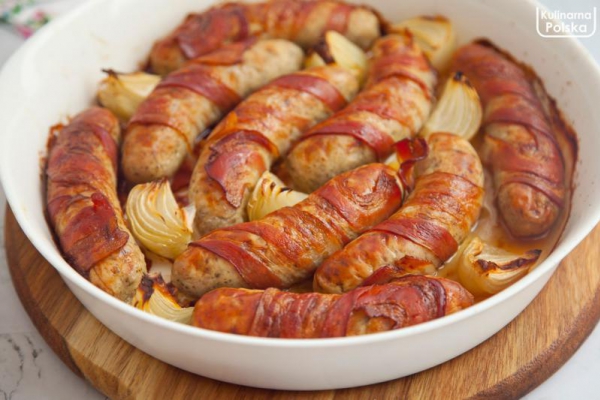 Pieczona biała kiełbasa zawijana w boczek z cebulką. Przepis na Wielkanoc
