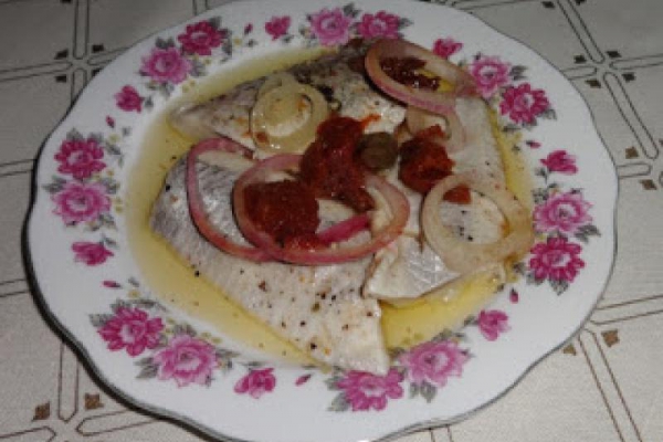 Marynowany filet śledzia z suszonymi pomidorami i cebulą.