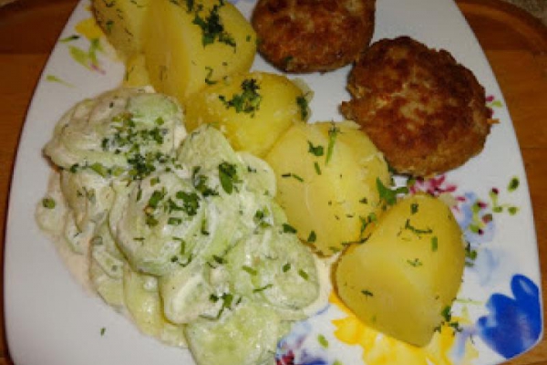 Kotlet mielony z młodymi ziemniakami i mizerią z ogórków.
