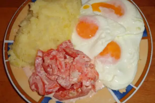 Jajka sadzone, ziemniaki i surówka z pomidorów i cebuli.