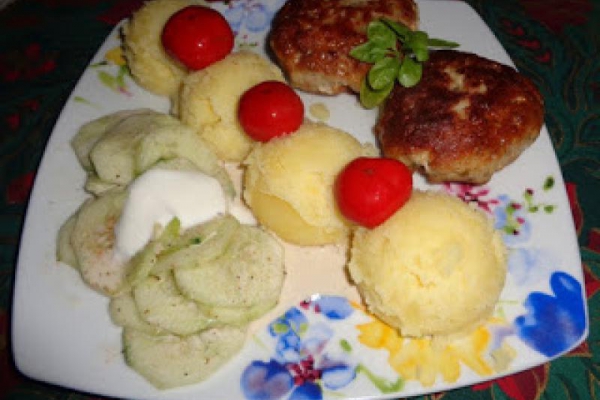 Kotlet mielony, ziemniaki, mizeria, marynowane papryczki czereśniowe.
