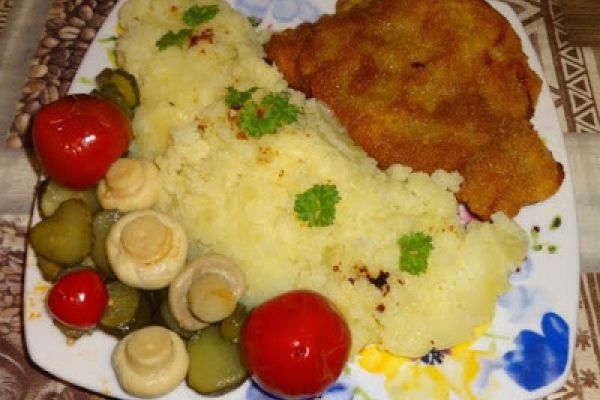 Kotlet schabowy z ziemniakami, marynowanymi plasterkami z ogórka, papryczkami chery i marynowanymi pieczarkami.
