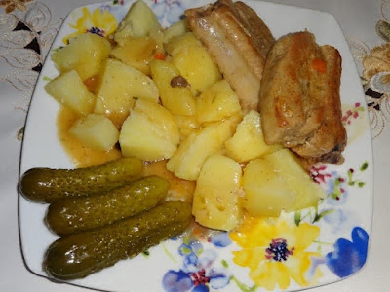 Żeberka wieprzowe z sosem, ziemniakami i  z marynowanymi ogórkami.